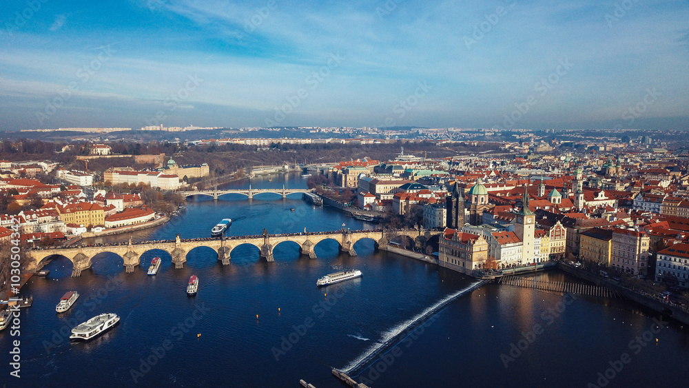Obraz premium Aerial view of the Vltava River and historic architecture in Prague under a clear blue sky