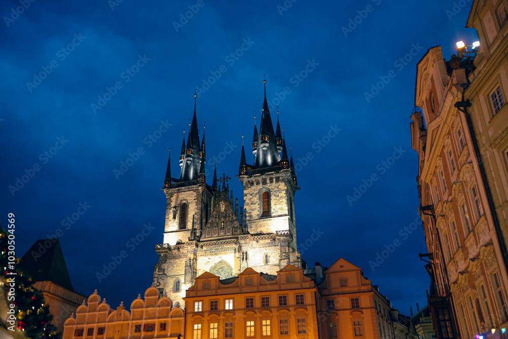 Fototapeta premium Twilight in Prague with gothic architecture and illuminated spires against a blue sky at night