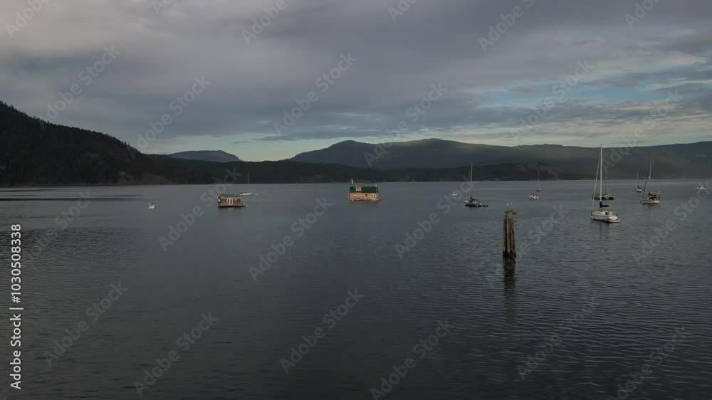 Drone approaching, from a floating house and a boat near the Cowichan Bay Wharf on Vancouver Island in Cowichan Bay, British Columbia, Canada Drone approaching, from a floating house and a boat near the Cowichan Bay Wharf on Vancouver Island in Cowichan Bay, British Columbia, Canada
