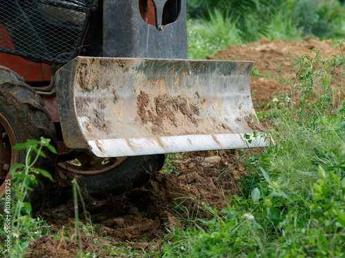 Tractor plowing soil in oil palm plantation photo