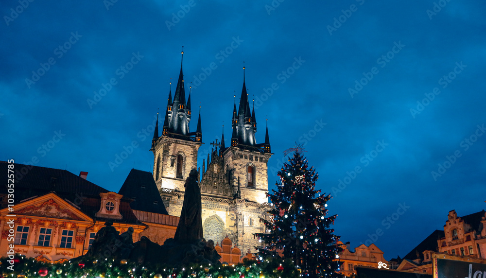 Fototapeta premium Christmas lights illuminate the towers of Týn Church against a twilight sky in Prague during the holiday season