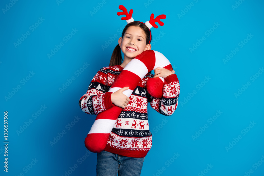 Photo of lovely cute girl wear red sweater christmas theme party hold big toy sweet candy event isolated on blue color background Photo of lovely cute girl wear red sweater christmas theme party hold big toy sweet candy event isolated on blue color background