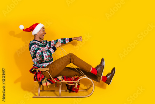 Full size photo of nice young man sledding empty space christmas festive time isolated on yellow color background