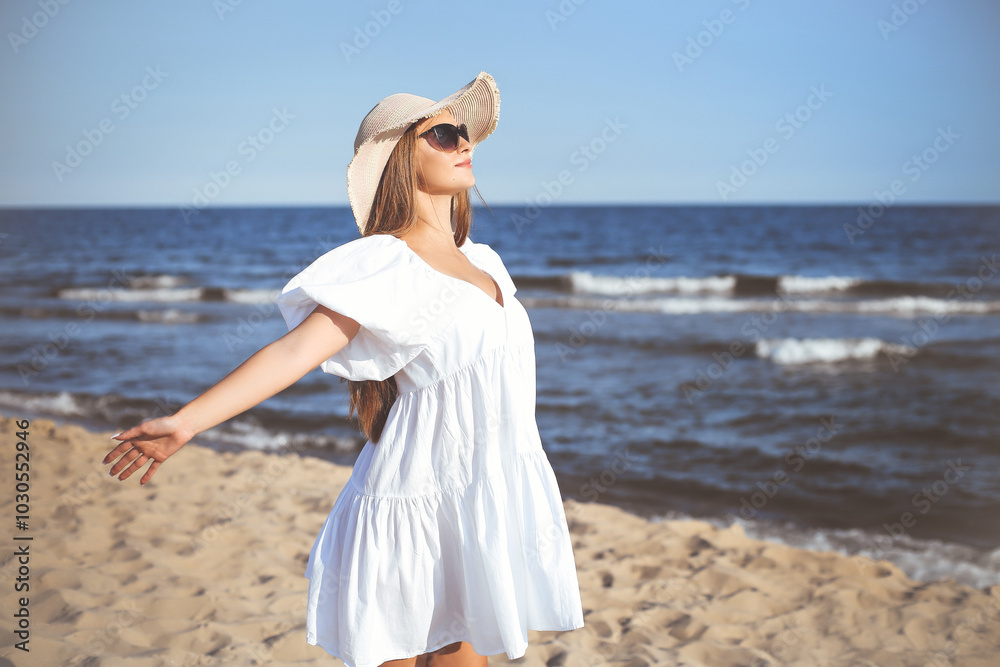 Happy blonde woman is on the ocean beach in a white dress and sunglasses, open arms Happy blonde woman is on the ocean beach in a white dress and sunglasses, open arms