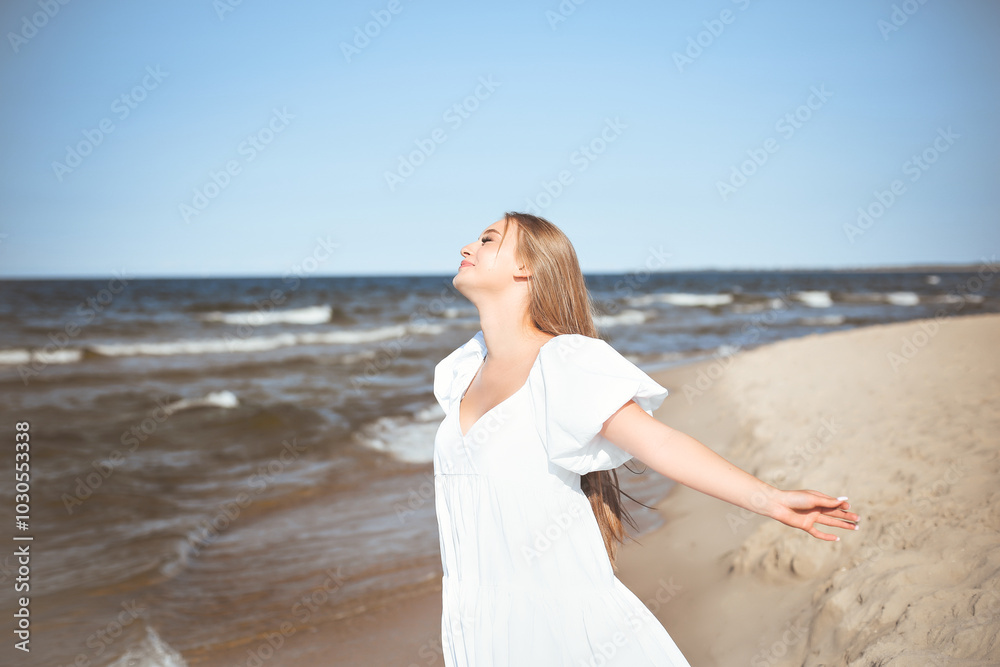 Happy smiling beautiful woman is on the ocean beach in a white summer dress, open arms Happy smiling beautiful woman is on the ocean beach in a white summer dress, open arms
