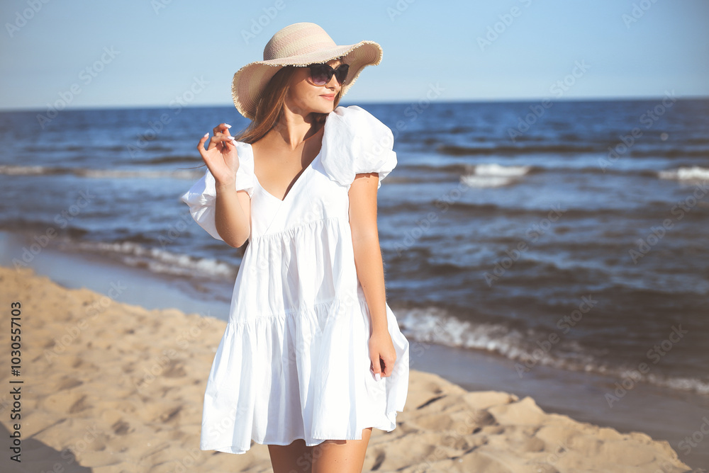 Happy smiling blonde woman is posing on the ocean beach with sunglasses and a hat Happy smiling blonde woman is posing on the ocean beach with sunglasses and a hat