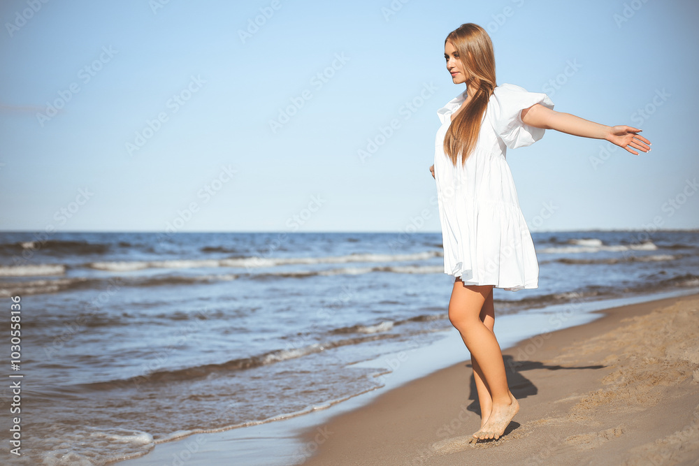 Happy smiling beautiful woman is walking on the ocean beach with open arms Happy smiling beautiful woman is walking on the ocean beach with open arms