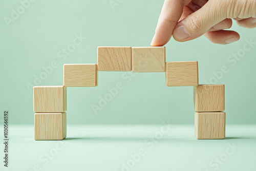 A hand is placing a block on top of another block, creating a bridge photo