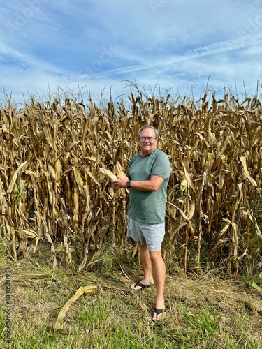 Canvas-taulu A man standing next to his family farmland with corn growing in the middle of th