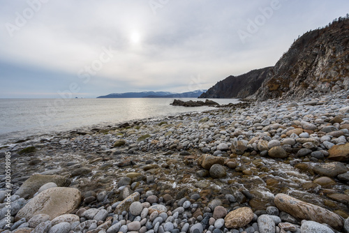 The coast of the Sea of ​​Okhotsk, Magadan Region, Russia. View of the rocky seashore. In the foreground is the mouth of the Kongali Creek. In the distance are capes. Nature of the Russian Far East. photo