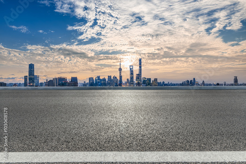 Empty asphalt road and cityscape with skyline in modern city at sunset