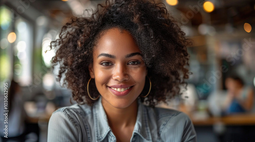 A smiling woman in casual attire stands indoors, exuding confidence and friendliness