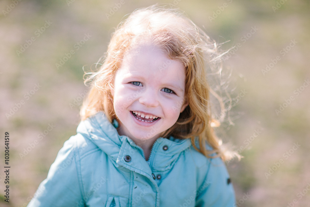 Portrait of an adorable beautiful happy smiling ginger-haired blond small child girl in a coat walking in a park Portrait of an adorable beautiful happy smiling ginger-haired blond small child girl in a coat walking in a park
