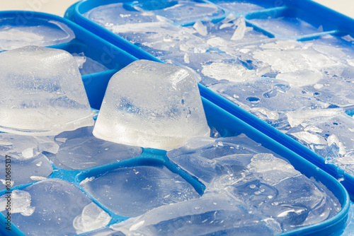 A close up image of several cracked and broken ice cubes in a blue ice cube tray.  photo