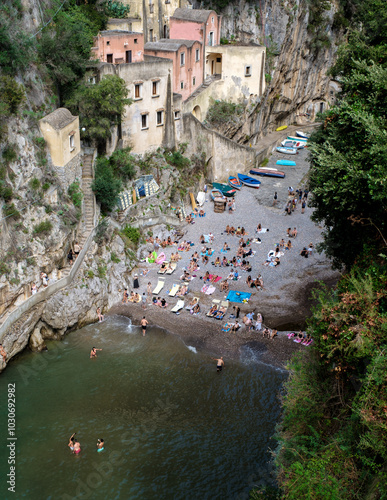 Visitors enjoy a sunny day on the Amalfi Coast, basking on the pebbled beach, while colorful boats line the shore, Fiordo Di Furore, The Furore beach Amalfi coast 