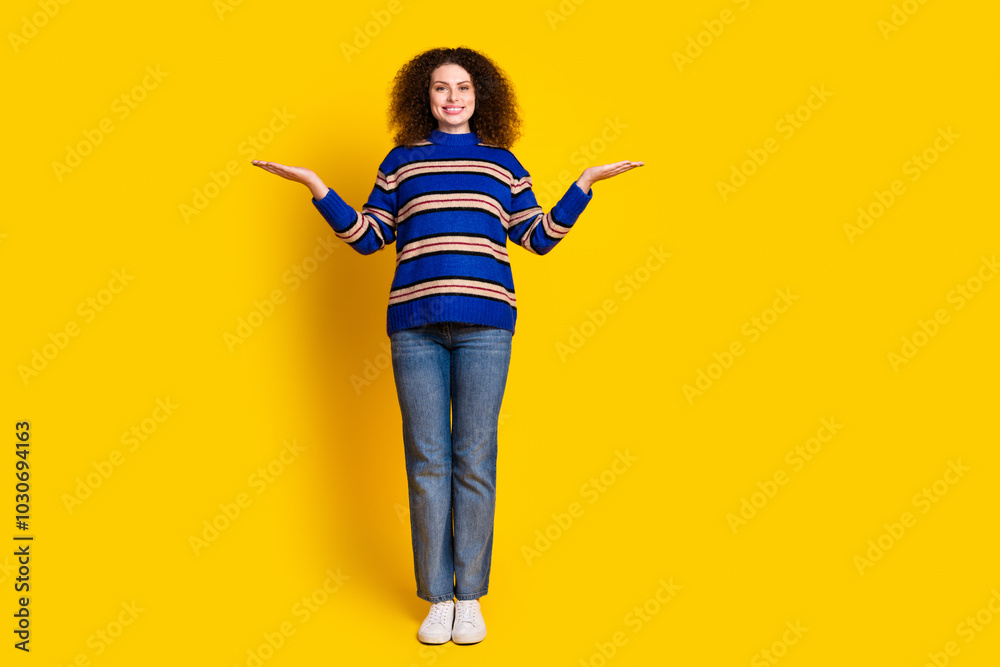 Full size photo of positive woman dressed striped sweater palms comparing products empty space isolated on yellow color background Full size photo of positive woman dressed striped sweater palms comparing products empty space isolated on yellow color background