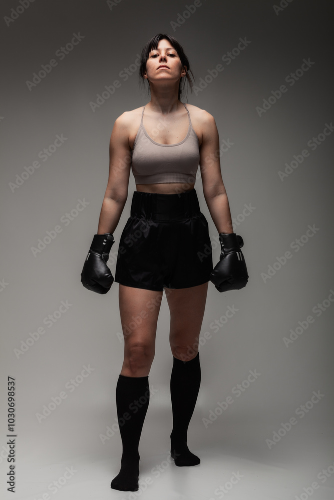 Confident young woman in boxing gear standing strong and ready to fight Confident young woman in boxing gear standing strong and ready to fight