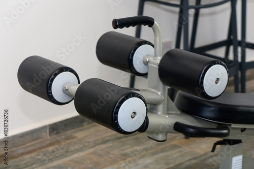 Adjustable Gym Equipment Highlighting Padded Rollers for Lower Body Workouts in a Modern Fitness Studio