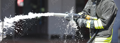 firefighter is spraying foam extinguishing agent with a powerful hose to control a fire