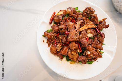 fried sticky ribs marinated in soy sauce and ginger sprinkled on white dish on marble table, chineese style, view from above photo