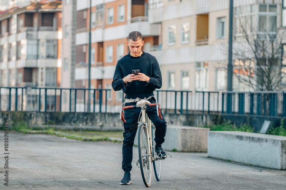Obraz premium urban young man with mobile phone on top of the bicycle in the street