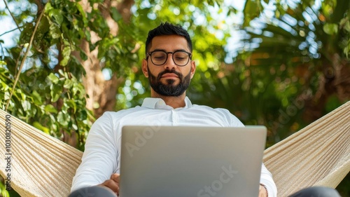 Businessman relaxing on a hammock with a laptop on his knees, worklife balance, digital nomad lifestyle
