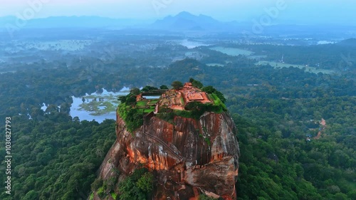 Numerous tourists walk by the ruins of fortress Sigiriya in Sri Lanka. Lion Rock from top view with hazy scenery at backdrop. photo