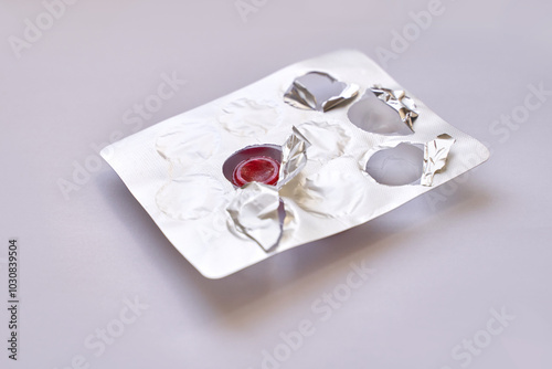 Fotografie Open blister pack with one remaining red pill on light background highlighting healthcare and medicine