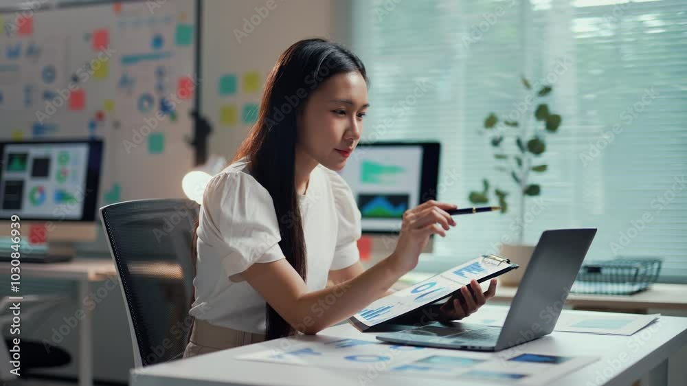 Young businesswoman analyzes financial data on a laptop while taking notes in her office, showcasing focus and determination Young businesswoman analyzes financial data on a laptop while taking notes in her office, showcasing focus and determination