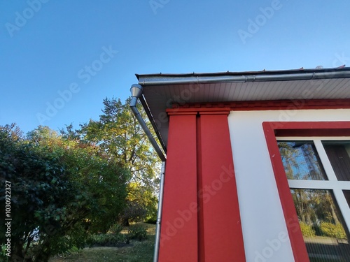 white building with a large window framed in red, featuring a neat reflection of the surroundings. The architecture captures the balance between clean, simple design and bold, colorful elements. photo