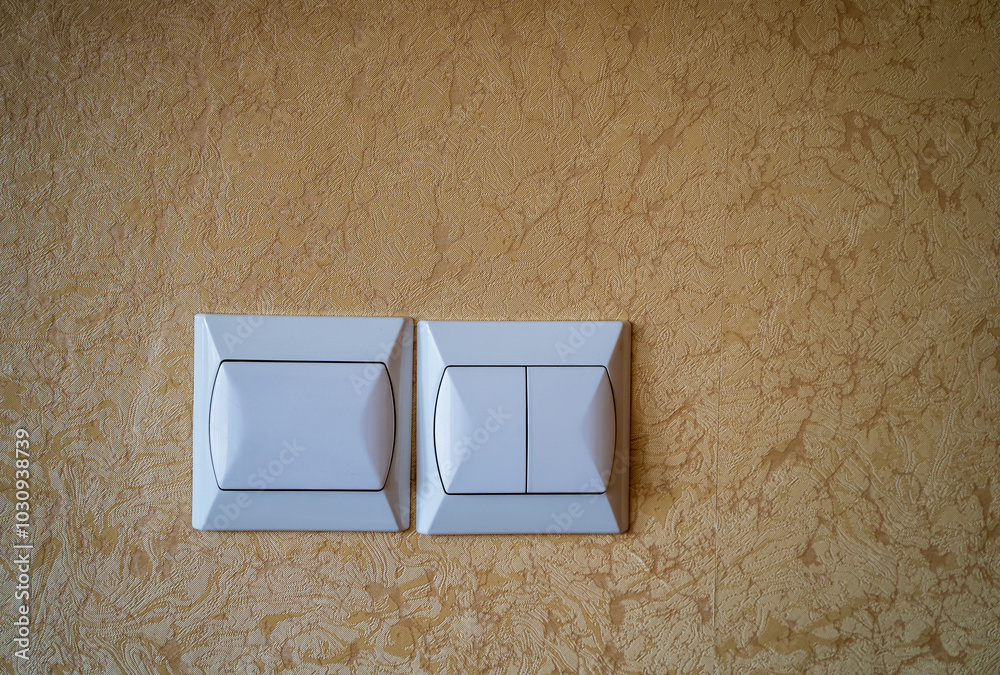 Two white light switches mounted on a textured beige wall.