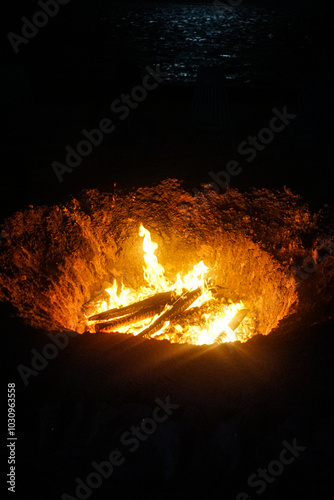 fire burning in a pit on the beach 