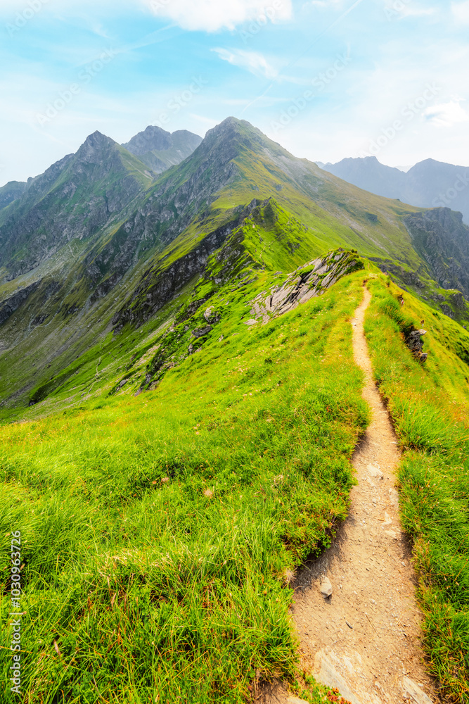 Fototapeta premium Hiking in Fagaras mountains on Iezerul Caprei peak over Transfagarasan serpentine road carpathian mountains. Mountains landscape