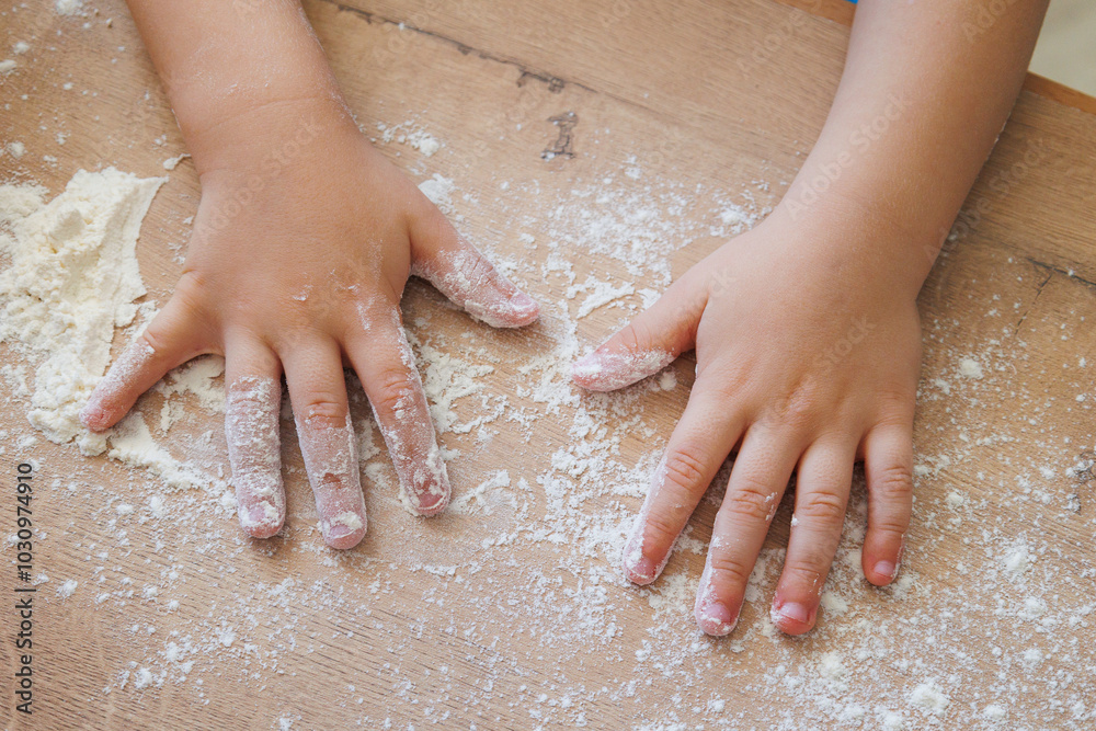 Children's hands in flour on a wooden surface during baking. Children's hands in flour on a wooden surface during baking.