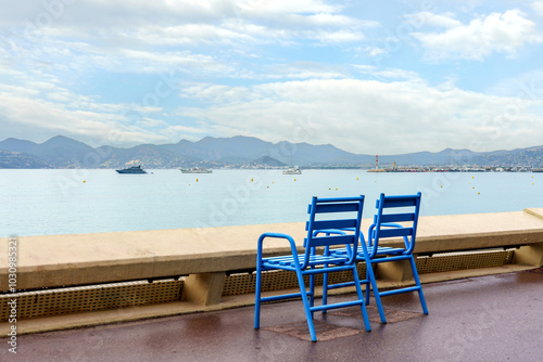 Two blue chairs on the Croisette promenade after rain in Cannes, France, French riviera, Cote D Azur. photo