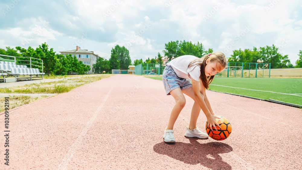 Cute child girl playing on sports ground with soccer ball outdoors Cute child girl playing on sports ground with soccer ball outdoors