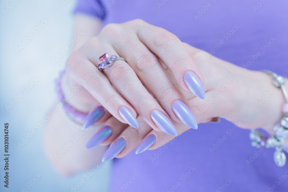Female hand with long nails and a lilac and blue nail polish Female hand with long nails and a lilac and blue nail polish