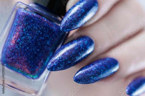 Photography Female hand with long nails and a blue and purple color nail polish
