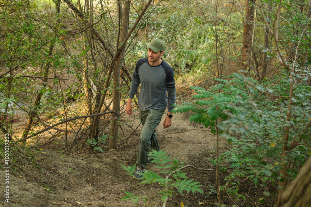 A man is hiking up a trail surrounded by dense greenery, taking in the beauty of nature. Dressed for outdoor activity, he moves confidently on the uneven terrain. A man is hiking up a trail surrounded by dense greenery, taking in the beauty of nature. Dressed for outdoor activity, he moves confidently on the uneven terrain.