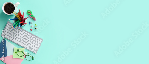 Workplace of graphic designer with PC keyboard, coffee and stationery on turquoise background with space for text, top view