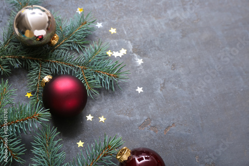 Christmas tree branches with balls and confetti on black background