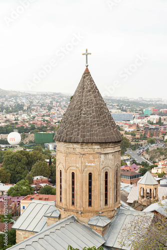 A historic church tower Norashen with a cross rises above the rooftops, Tbilisi, Georgia - 10 September, 2024 photo