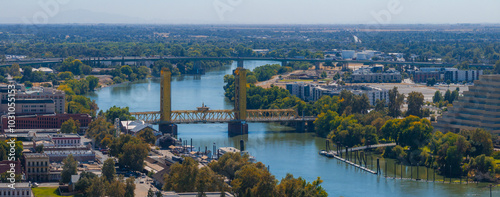 Aerial perspective of Sacramento, California, highlighting the yellow gold Tower Bridge over the Sacramento River, with urban and natural landscapes. photo