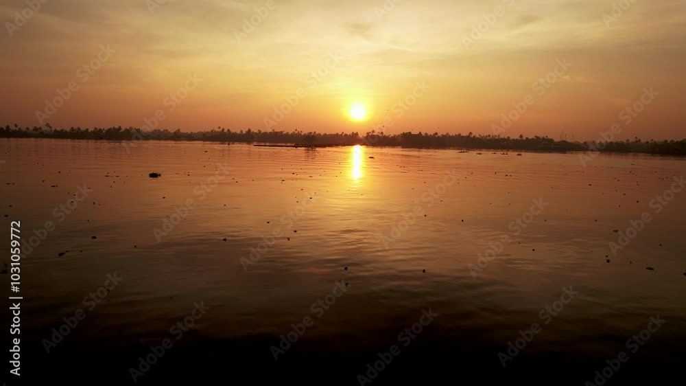 Stunning golden sunset casting warm reflections over serene lake water, with a silhouette of distant trees lining the horizon Stunning golden sunset casting warm reflections over serene lake water, with a silhouette of distant trees lining the horizon