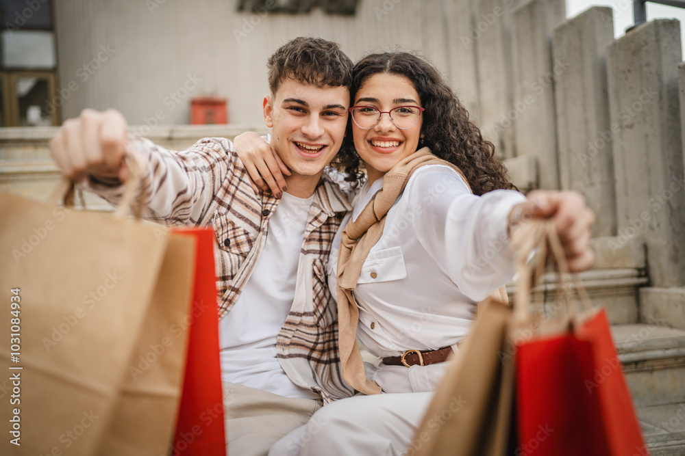 portrait of hugged couple sit on stairs and hold shopping bags portrait of hugged couple sit on stairs and hold shopping bags