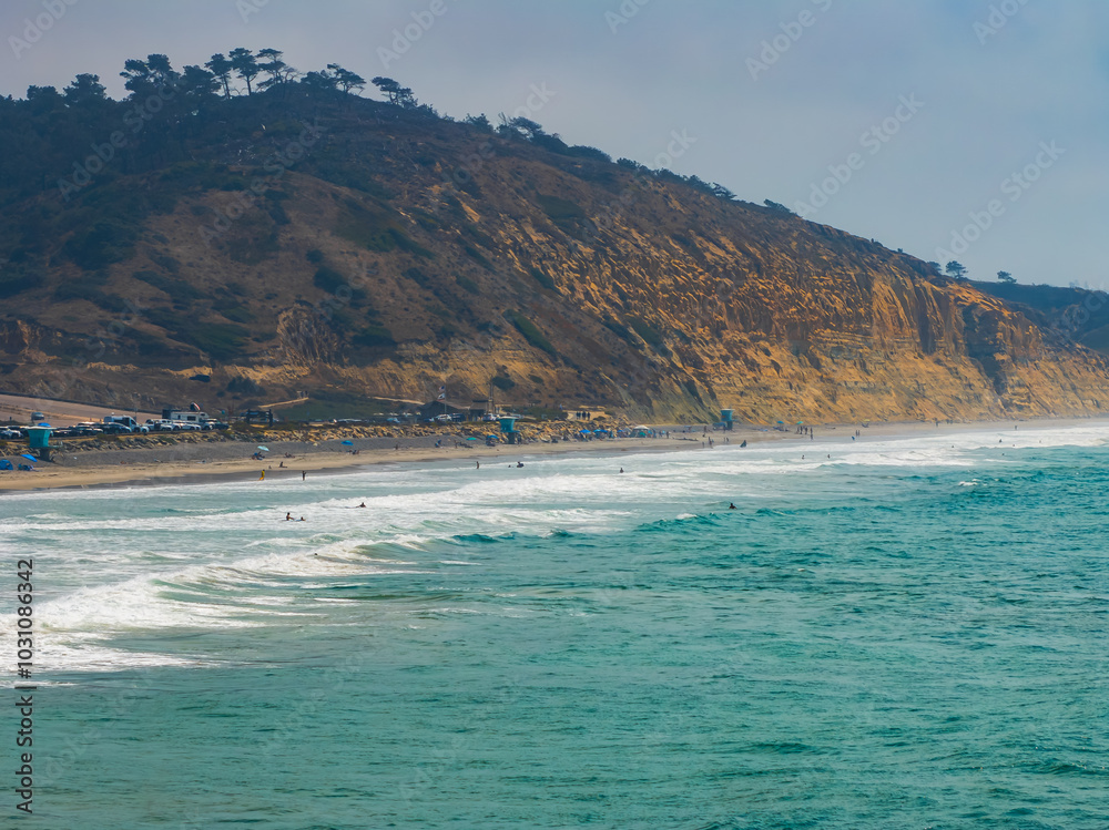 Torrey Pines State Beach in San Diego features rugged cliffs with sparse vegetation and Torrey pine trees, overlooking surfers in the vibrant blue ocean. Torrey Pines State Beach in San Diego features rugged cliffs with sparse vegetation and Torrey pine trees, overlooking surfers in the vibrant blue ocean.