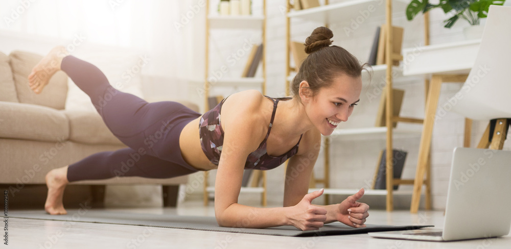 Fitness girl training yoga, watching online videos on laptop in the living room at home Fitness girl training yoga, watching online videos on laptop in the living room at home