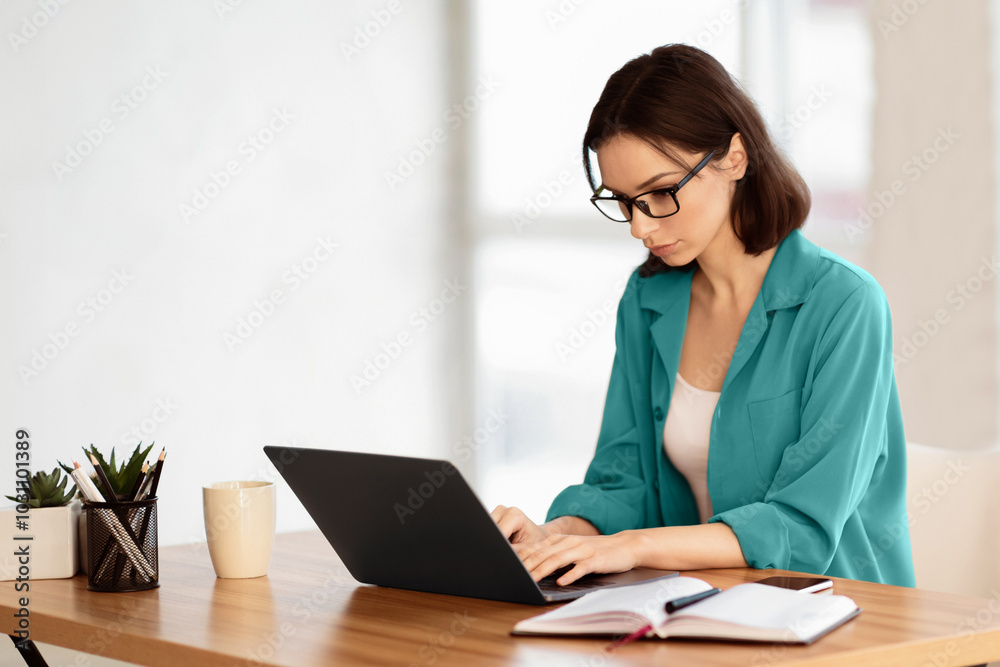 Home Office. Portrait of young female manager wearing specs and brown shirt using laptop, working remotely. Copy space Home Office. Portrait of young female manager wearing specs and brown shirt using laptop, working remotely. Copy space