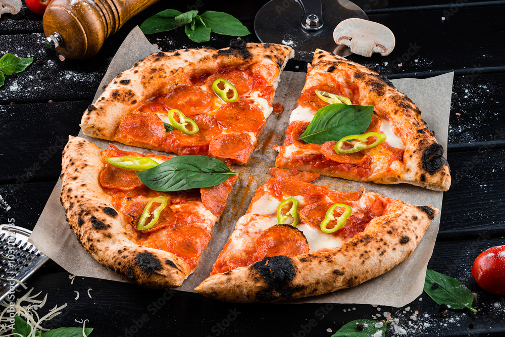 Φωτογραφία Traditional Italian pepperoni pizza with mozzarella, tomato sauce, jalapeno, spinach on thick dough cut into pieces from the oven