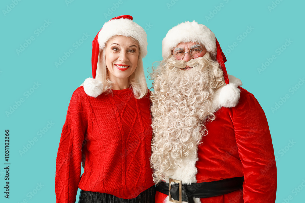 Φωτογραφία Happy Santa Claus and beautiful mature woman in Christmas hats on blue backgroun